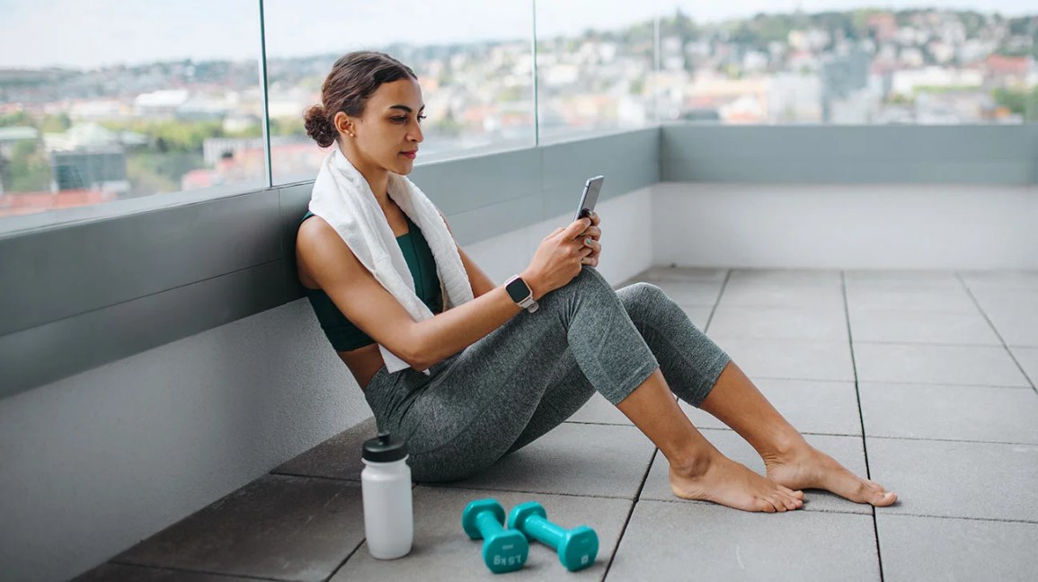 Woman looking at her iphone after finishing a workout 